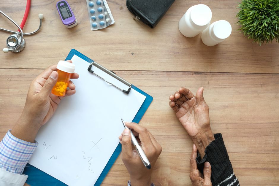 Clinician and client reviewing a prescription bottle over a chart at a desk