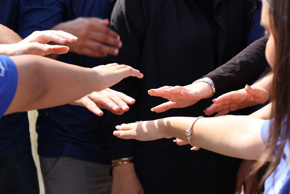 Diverse group of people placing hands together, symbolizing community and support